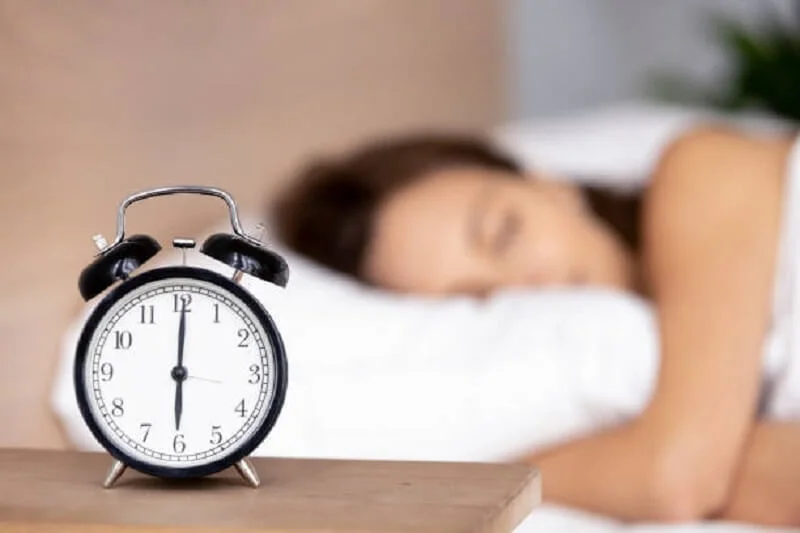 Alarm clock on table and Woman sleeping