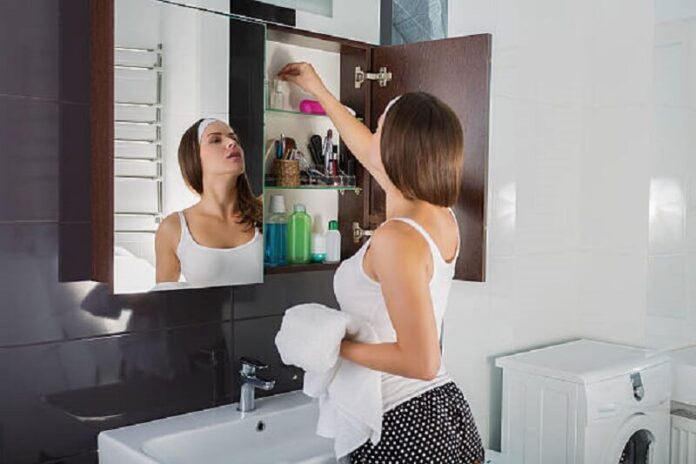 Woman putting something into the bathroom cabinet
