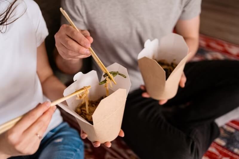 man and woman eating Chinese food