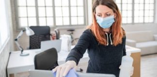 Woman wearing mask and cleaning the monitor