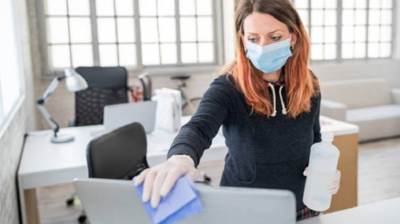 Woman wearing mask and cleaning the monitor