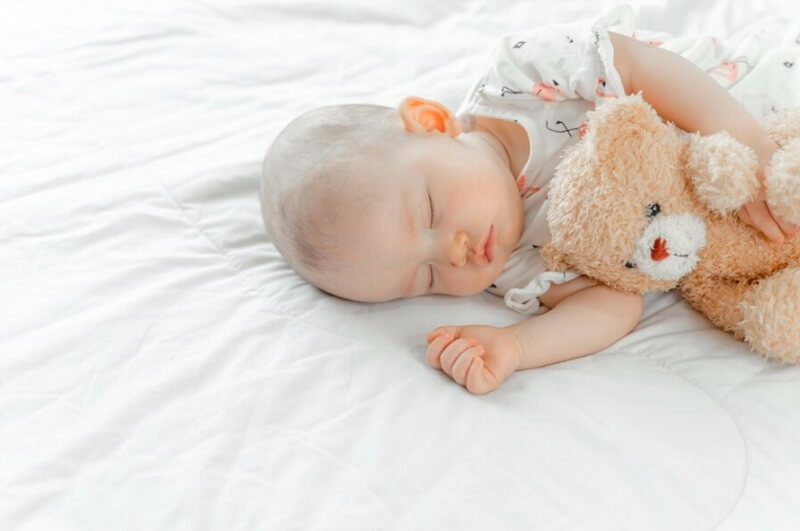 baby sleeping with a teddy bear
