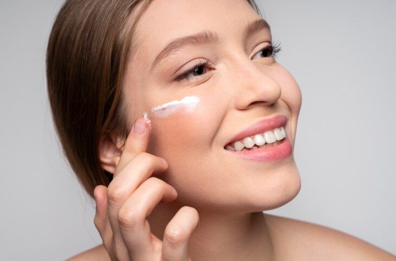 girl smiling and applying face cream