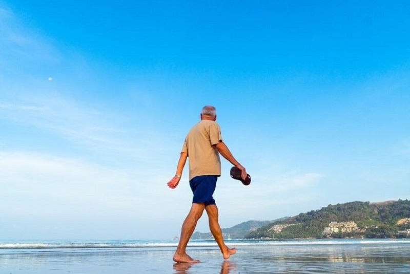 Old man walking in beach