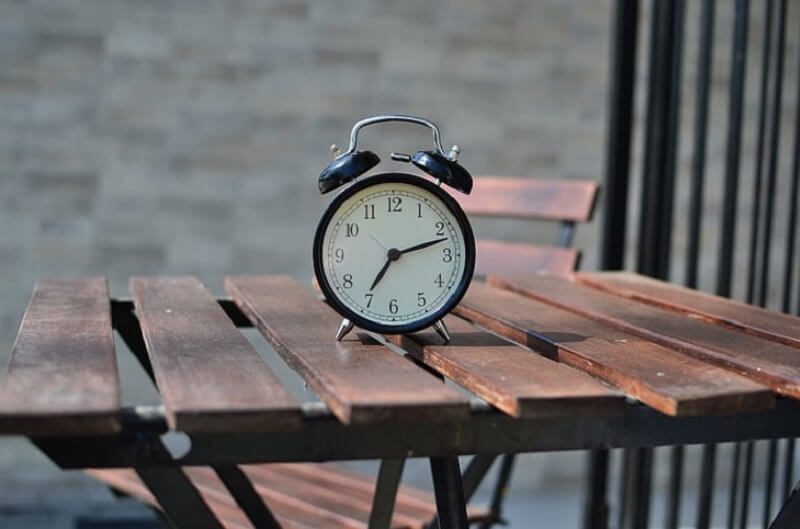 black-color-alarm-clock-on-wooden-table