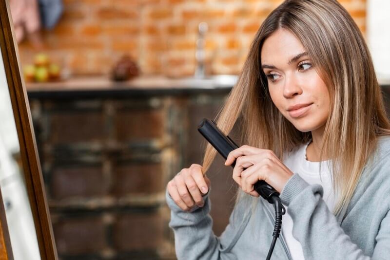girl straightening her hair at home